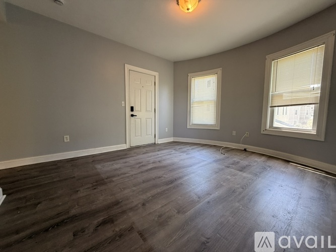 A room with a wooden floor and a window with blinds.