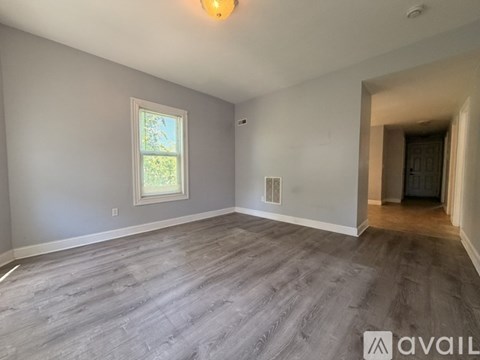 A spacious room with grey flooring and a window.