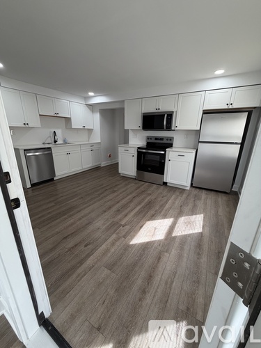 A kitchen with white cabinets and a wooden floor.
