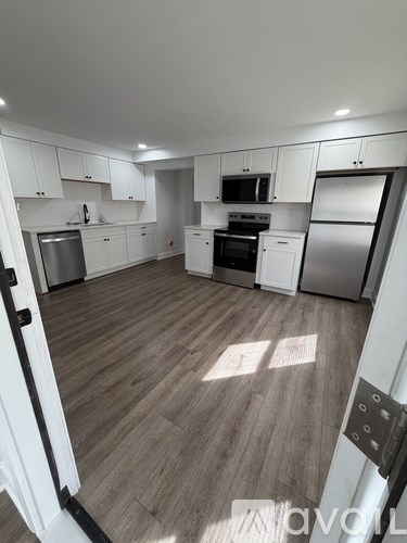 A kitchen with white cabinets and a wooden floor.