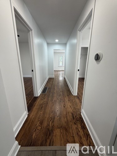 A hallway with wood flooring and white walls.