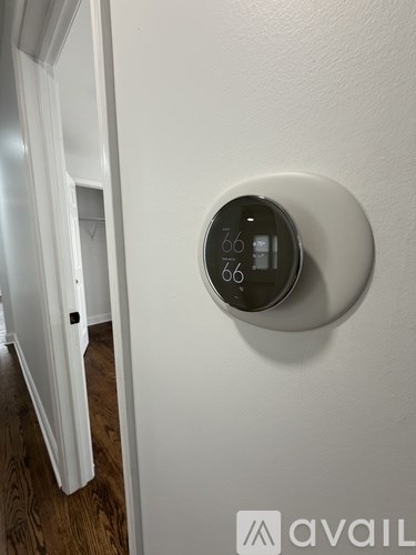 A thermostat on a wall showing a temperature of 66 degrees.