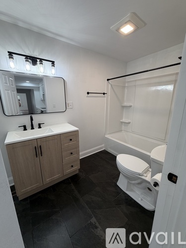 A bathroom with a white toilet, sink, and mirror.