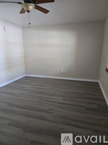 A room with a ceiling fan and wooden flooring.