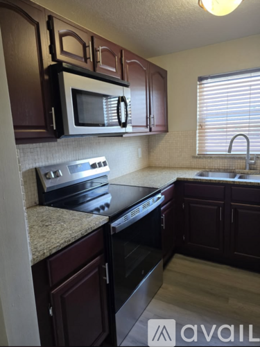 A kitchen with dark wood cabinets and a black stove top oven.