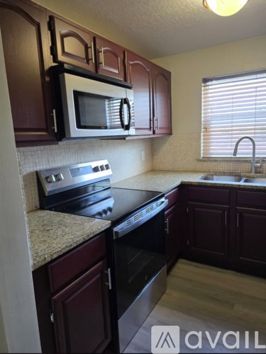 A kitchen with dark wood cabinets and a black stove top oven.