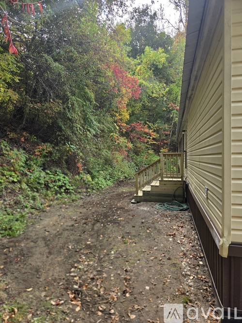 A dirt path leads to a house with a deck.