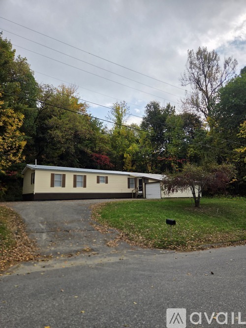 A house with a driveway and trees in the background.