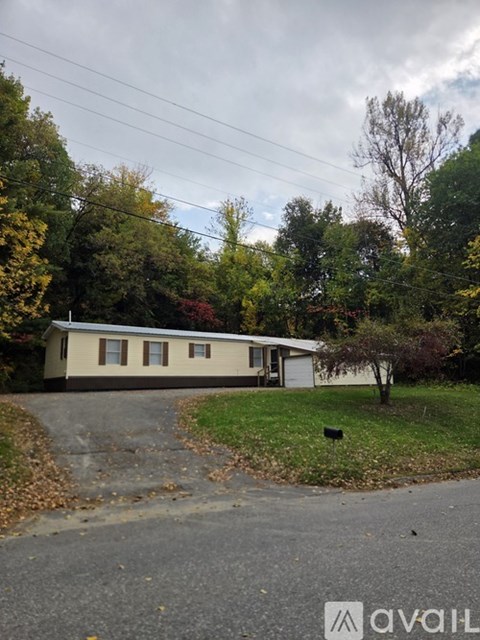 A house with a driveway and trees in the background.