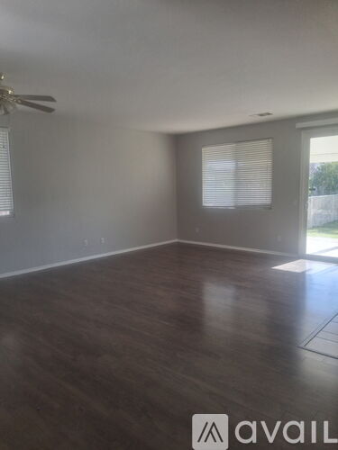 A room with a ceiling fan and wooden flooring.