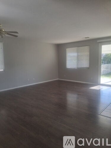 A room with a ceiling fan and wooden flooring.