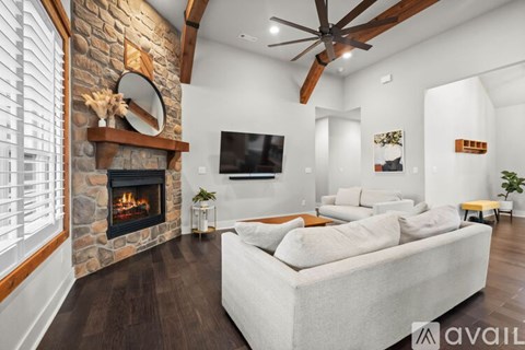 A modern living room with a stone fireplace and a large white couch.