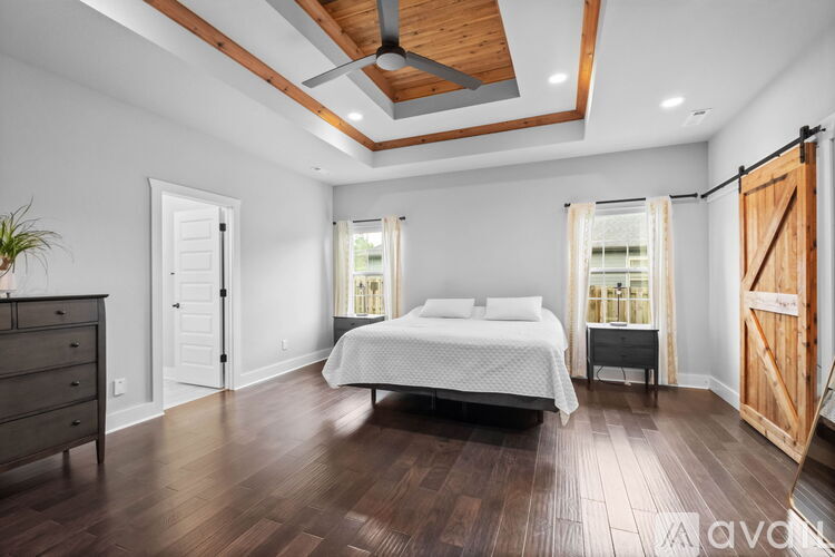 A bedroom with a bed, dresser, and wooden floors.