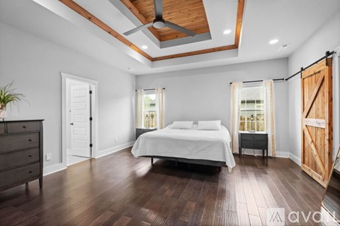 A bedroom with a bed, dresser, and wooden floors.