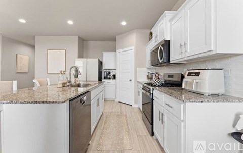 A kitchen with white cabinets and a granite countertop.