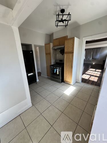 A kitchen area with a black fridge and wooden cabinets.