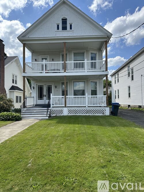 A white two-story house with a balcony and a front porch.
