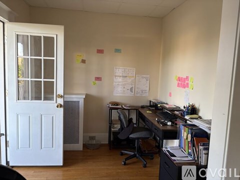 A room with a desk, chair, and sticky notes on the wall.