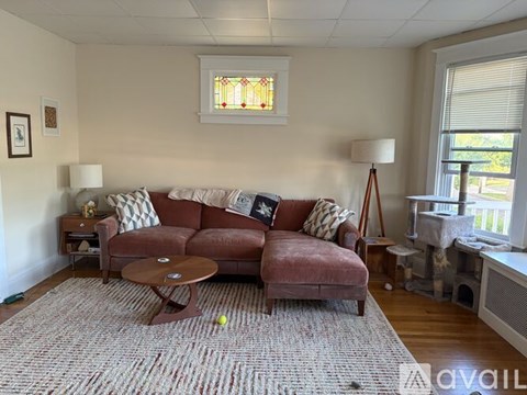 A living room with a brown couch and a round table in the middle.