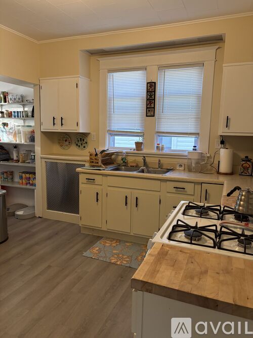A kitchen with a white stove top oven and wooden countertop.