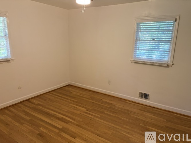 A room with wooden flooring and a window with blinds.