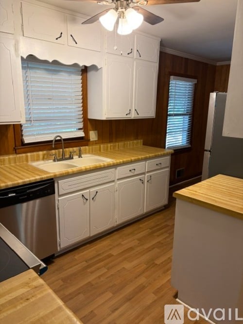 A kitchen with white cabinets and a wooden island.