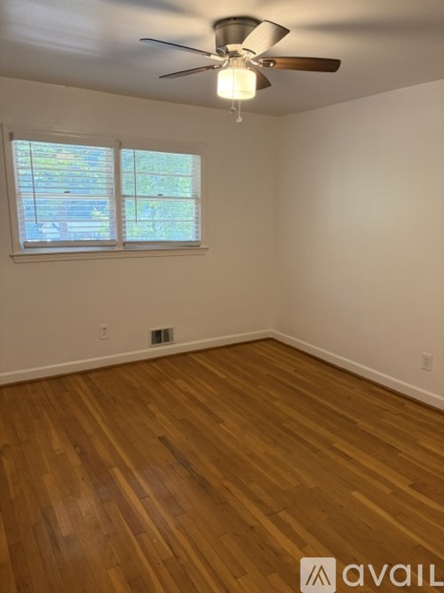 A room with a ceiling fan and wooden flooring.