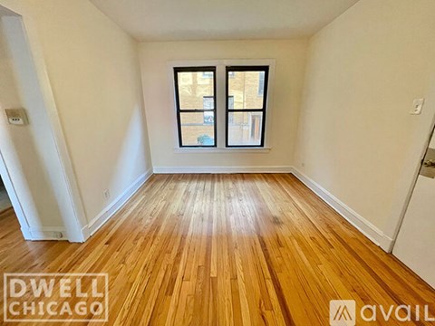 A room with wooden flooring and a window showing a view of a building outside.