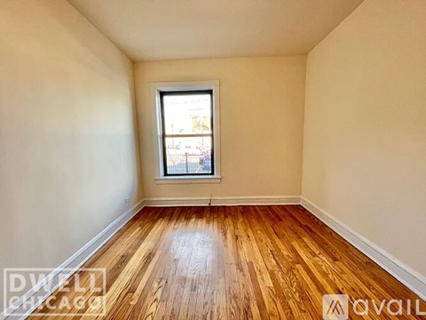 A room with wooden floors and a window showing a view of a street.