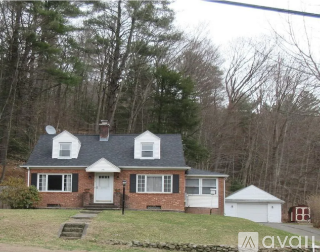 A house with a white door and windows is surrounded by trees.