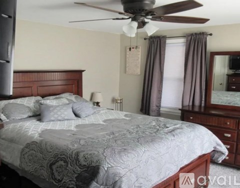 A bedroom with a large bed and a ceiling fan.