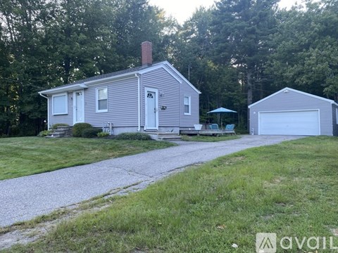 A house with a driveway and a garage is surrounded by trees.
