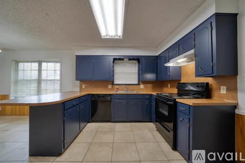 A kitchen with dark blue cabinets and black appliances.