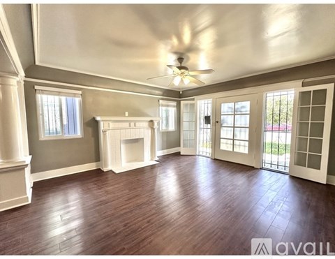 A spacious room with wood flooring and a ceiling fan.