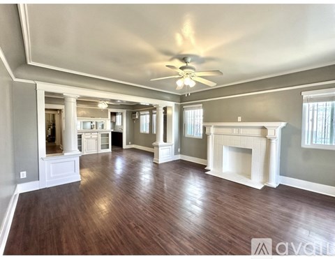 A large empty room with wood floors and a fireplace.
