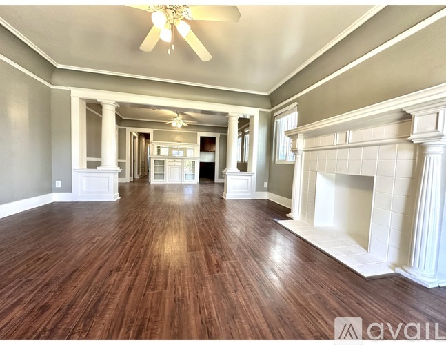 A spacious room with wooden floors and a fireplace.