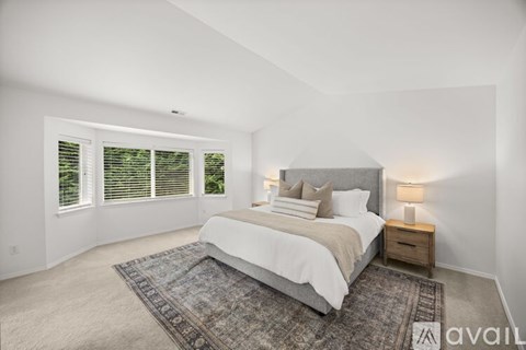 A bedroom with a large bed and a window with blinds.