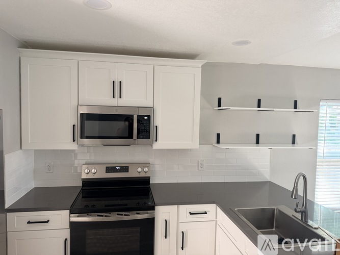 A kitchen with white cabinets and black countertops.