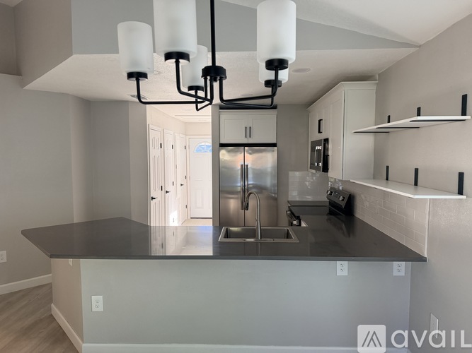 A modern kitchen with a black countertop and a stainless steel sink.