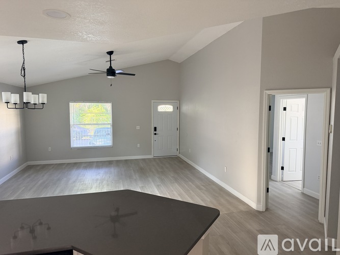 A spacious room with a ceiling fan and a large window.