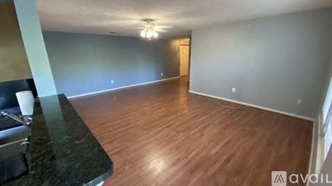 A room with wooden flooring and a kitchen area with a granite countertop.