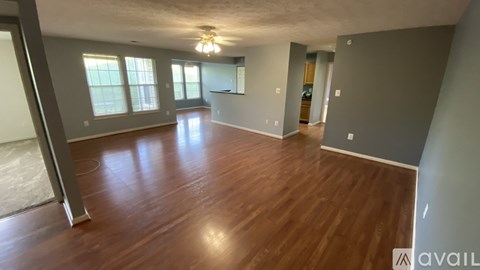 A spacious room with wooden flooring and a ceiling fan.