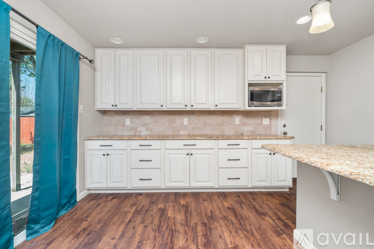 A kitchen with white cabinets and a granite countertop.