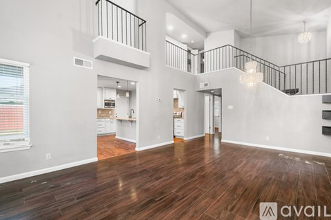 A spacious living room with hardwood floors and a staircase with a metal railing.