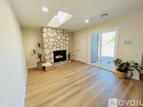 A living room with a stone fireplace and wooden flooring.
