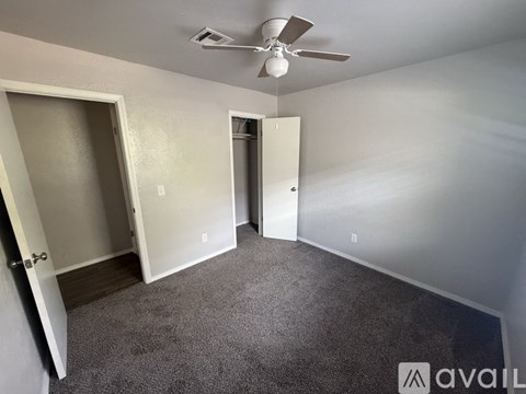 A room with a ceiling fan and two doors.