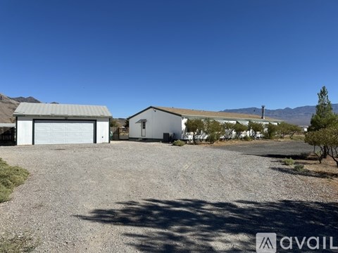 A gravel driveway leads to a white garage with a metal roof.