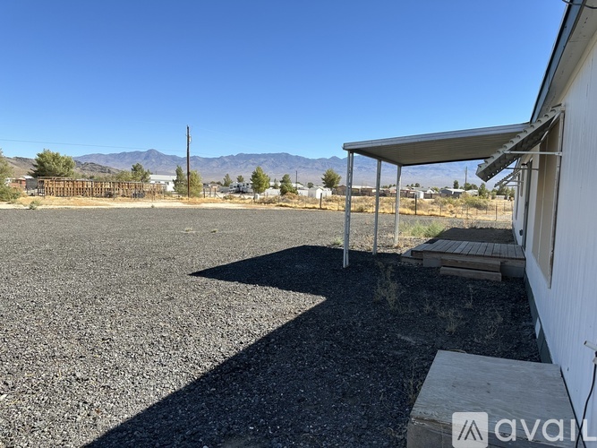 A gravel parking lot with a white building and a metal awning.