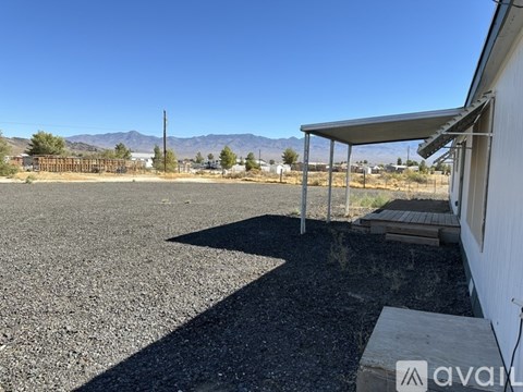 A gravel parking lot with a white building and a metal awning.