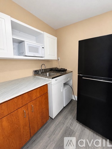 A kitchen with a black refrigerator, white dishwasher, and microwave.